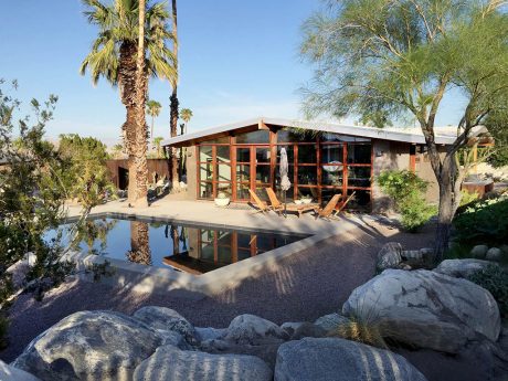 A modernist desert oasis with a stunning pool, wooden beams, and lush greenery.