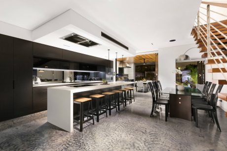 Modern kitchen with black cabinetry, wooden accents, and a large dining table.