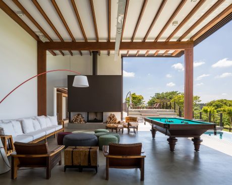 Spacious indoor-outdoor living area with wooden beams, fireplace, and expansive views.
