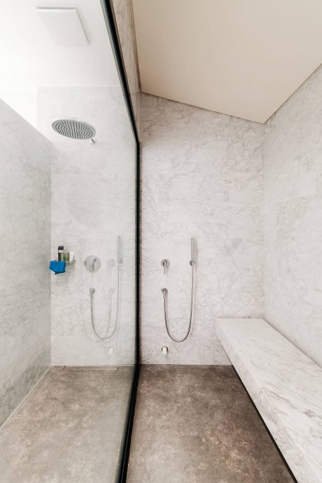 Modern bathroom with marble tiles, recessed lighting, and dual-head shower system.