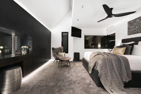 Sleek, contemporary bedroom with black cabinetry, plush textiles, and modern ceiling fan.
