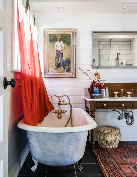 A cozy bathroom featuring a claw-foot tub, ornate vanity, and a framed artwork on the wall.
