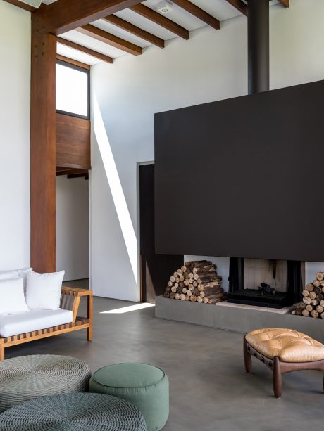 Modern living room with wooden beams, concrete fireplace, and minimalist furnishings.