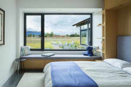 A cozy bedroom with a large window overlooking a scenic outdoor landscape.