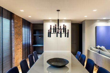 Modern dining room with sleek lighting fixture, wooden accents, and contemporary furnishings.
