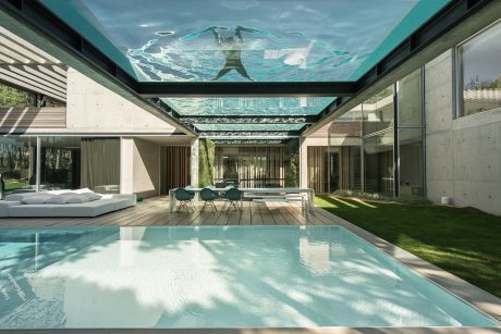A modern, open-concept home with a spacious patio, lush lawn, and an inviting swimming pool.
