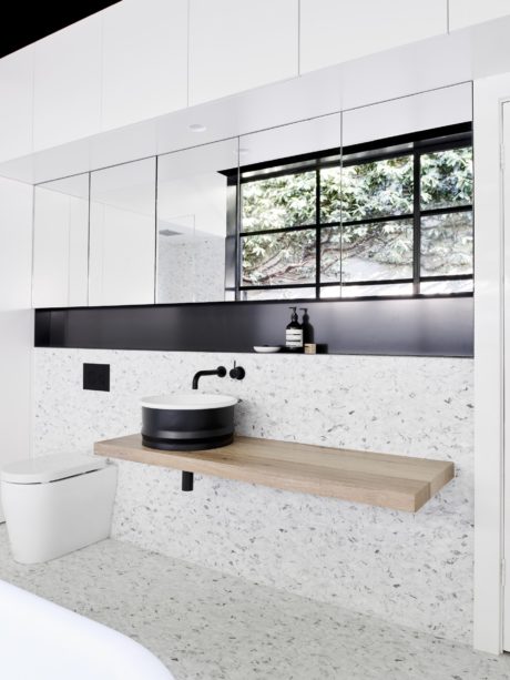 Minimalist bathroom design with sleek black fixtures, textured marble countertop, and modern vanity.