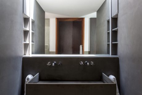 Minimalist bathroom with dark vanity, recessed mirror, and built-in shelving.