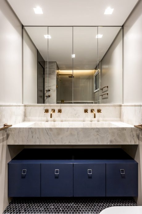Sleek bathroom with marble vanity, recessed lighting, and navy blue cabinetry.
