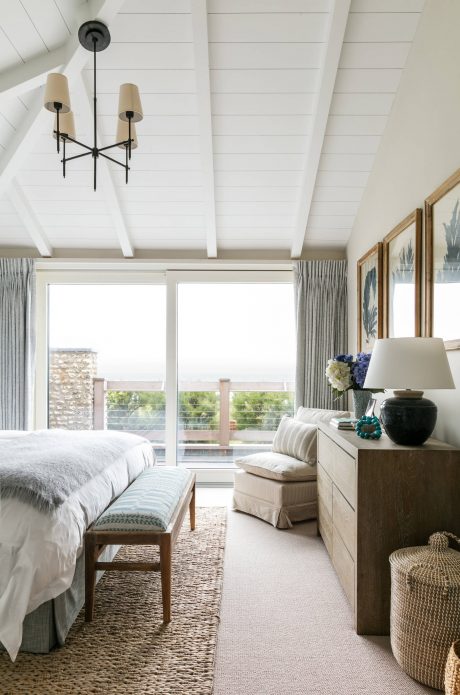 Cozy bedroom with vaulted ceilings, large windows, and neutral color palette.
