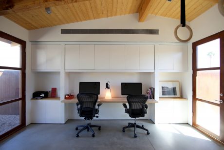 Spacious home office with wooden ceiling, built-in cabinets, and large windows.
