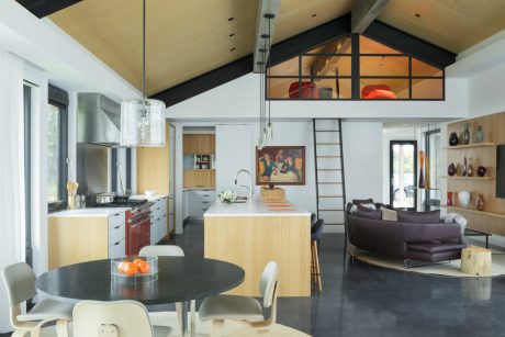 Spacious open-plan kitchen and living room with vaulted ceiling, wood beams, and modern decor.