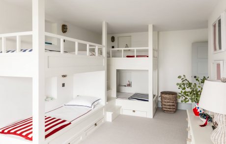 Bright, modern bunk-bed room with built-in shelving and storage units, minimalist decor.