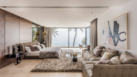 Spacious, modern bedroom with floor-to-ceiling windows, plush furnishings, and abstract art.