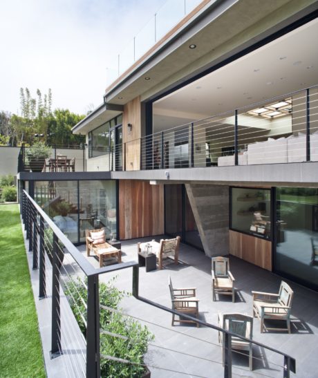 A modern, multi-level glass and steel structure surrounded by a lush green lawn.