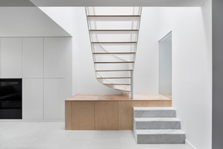 Sleek, minimalist staircase with floating wooden steps and marble risers in bright, airy space.