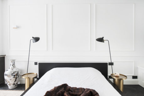 Minimalist bedroom design with black headboard, modern lamps, and accent vase.