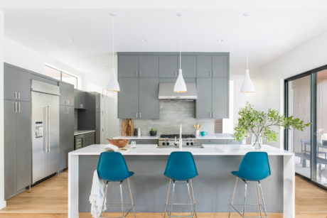 Sleek, modern kitchen with grey cabinetry, white countertops, and turquoise bar stools.