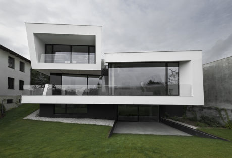 Modern minimalist home design with sleek glass walls, clean lines, and a grassy yard.