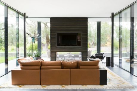 Modern interiors with wooden panels, glass walls, and a cozy leather sofa.