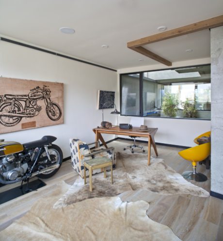 Spacious modern workspace with wood accents, exposed beams, and vintage motorcycle.