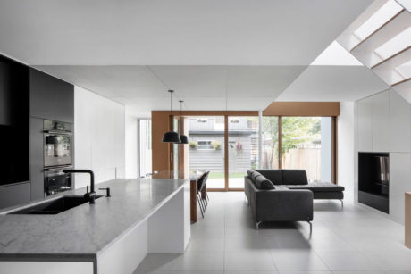 Modern open-concept kitchen with sleek gray cabinets, large windows, and a cozy living room.