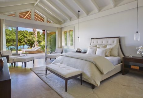 Spacious bedroom with vaulted ceiling, large windows overlooking tropical foliage.