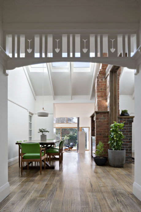 A modern dining area with vaulted ceilings, exposed brick, and wooden floors.