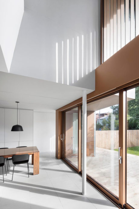 Modern home interior with large windows, wood framing, and linear lighting.