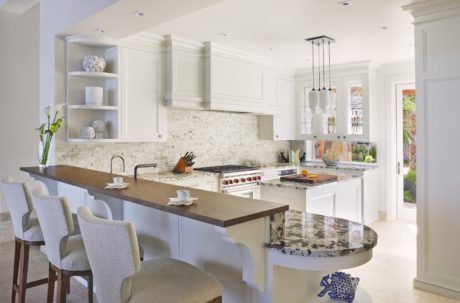 Spacious kitchen with modern cabinetry, stone backsplash, and curved counter seating.