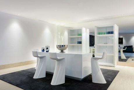 A sleek, modern dining room with minimalist white furniture and built-in shelving.