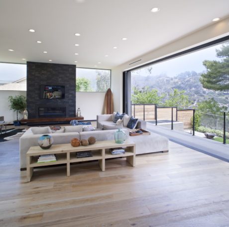 Spacious living room with large windows, sleek furniture, and a rustic wooden coffee table.
