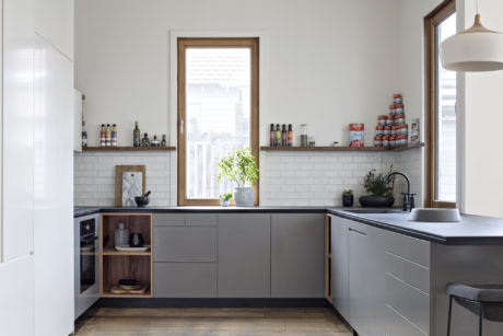 A modern kitchen with gray cabinets, subway tile backsplash, and wooden accents.