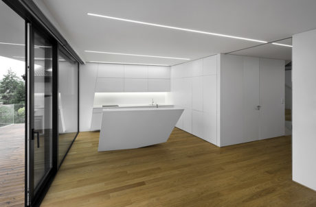 Modern, minimalist interior with wood flooring, sleek white cabinetry, and recessed lighting.