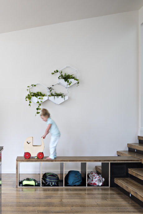 A modern, minimalist entryway with a geometric plant display and a child's toy car.