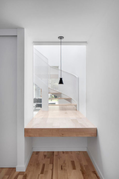 Minimalist staircase with wooden treads and a single pendant light fixture.