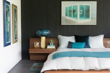 Sleek, modern bedroom design with dark wood furnishings, vibrant blue accents, and abstract artwork.