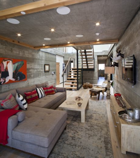 Spacious open-concept living area with concrete walls, wooden beams, and vibrant decor.