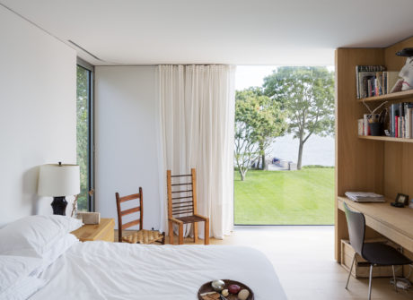 Bright, modern bedroom with large windows, wooden accents, and a serene outdoor view.