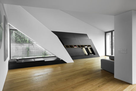 Minimalist living space with modern furniture, angled walls, and hardwood flooring.
