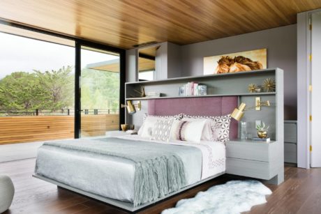 Spacious modern bedroom with wood-paneled ceiling, large windows, and built-in shelving.