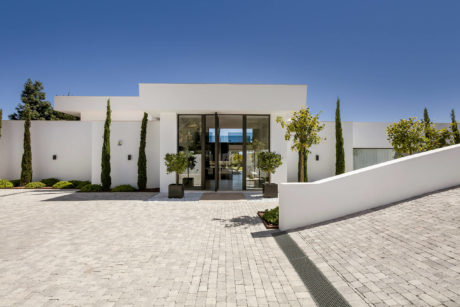 Contemporary white stucco building with glass entryway and landscaped courtyard.