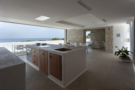 Sleek, modern kitchen with stone walls, open floor plan, and ocean view.