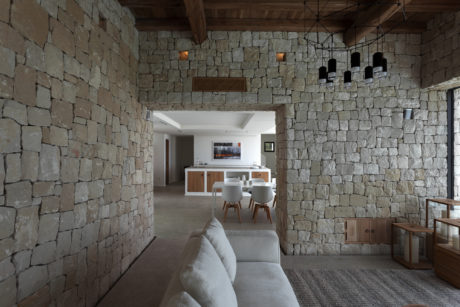 Rustic stone walls, wooden beams, and modern furniture create a cozy yet stylish space.