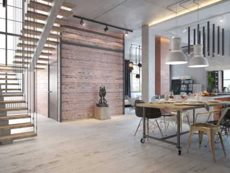 Spacious open-concept loft with exposed brick walls, wooden stairs, and industrial-style decor.