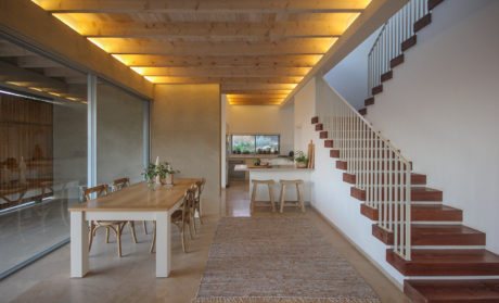 Spacious open-plan living area with wooden beams, dining table, and staircase.