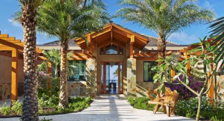 Luxurious tropical villa with wooden accents, stone walls, and lush landscaping.