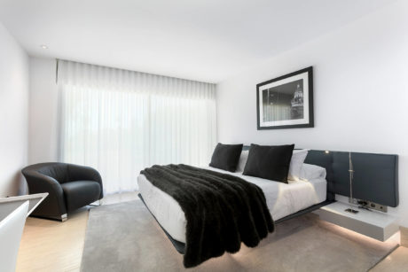 Spacious, modern bedroom with minimalist decor, large windows, and a cozy black-and-white color scheme.