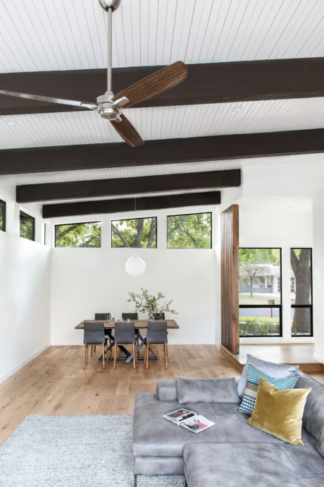 Sleek, modern interior with floor-to-ceiling windows, wooden beams, and a ceiling fan.