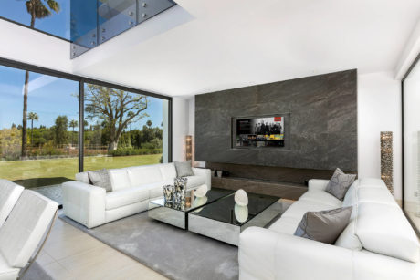 Sleek modern living room with large windows, stylish furniture, and stone accent wall.
